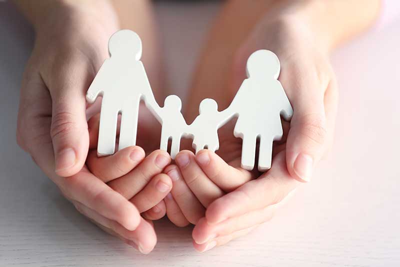 Mains tenant une statuette blanche représentant une famille avec deux enfants