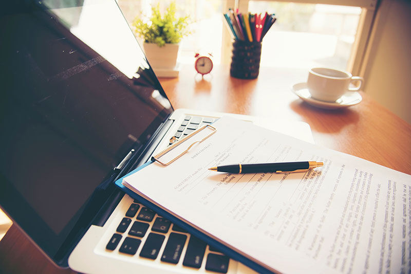 Gros plan d'un ordinateur avec papier, stylo et tasse à café